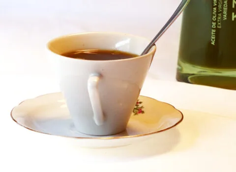 Taza de café acompañada de aceite de oliva virgen extra Isbilya, representando una experiencia sensorial única.