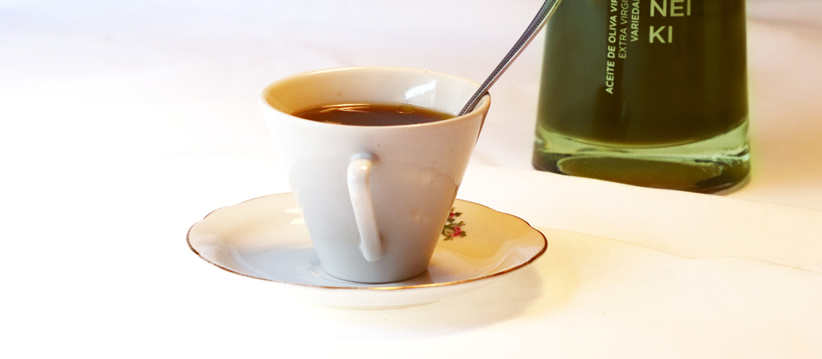 Taza de café acompañada de aceite de oliva virgen extra Isbilya, representando una experiencia sensorial única.