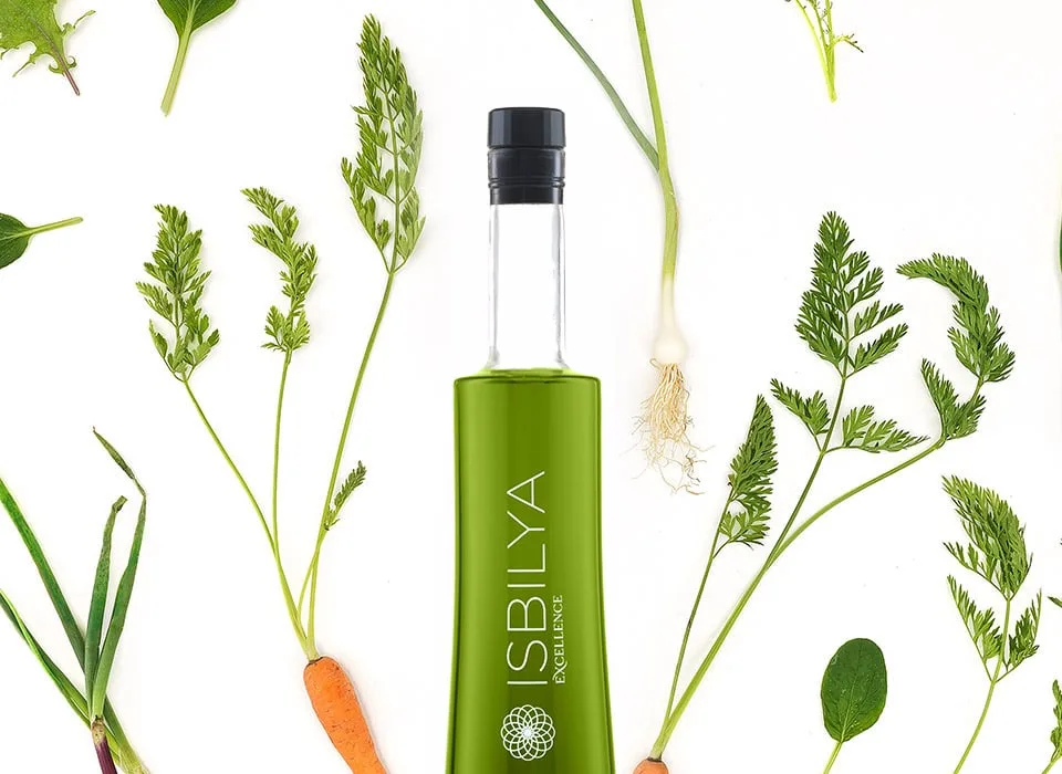 Botella AOVE Premium Isbilya rodeada de vegetales frescos