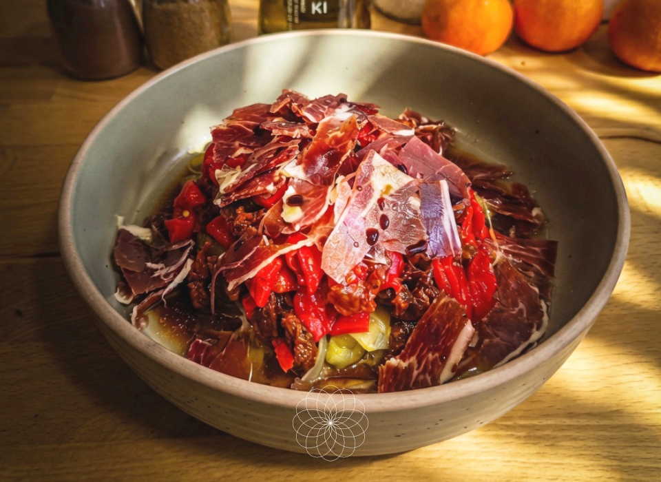 Plato con ensalada de puerros, piminetos asados, jamón y AOVE Isbilya Koroneiki sobre encimera de madera