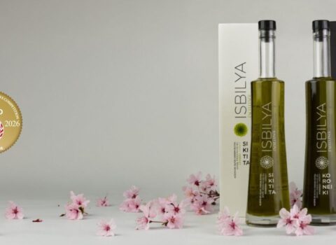 Botellas y estuches de isbilya sikitita y koroneiki sobre flores de cereza y el logo que acredita la medalla de oro en el concurso internacional de aceite de oliva de Japón.